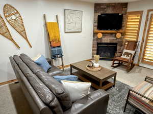 Living area with carpet flooring and a stone fireplace