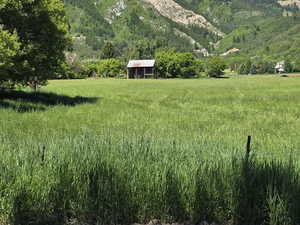 View of green lawn with a mountain view, an outbuilding, and a view of rural / pastoral area