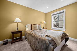 Additional guest bedroom with queen bed, storm window, and open closet with dresser.
