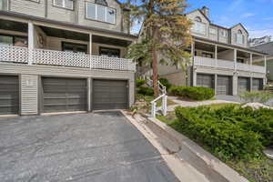 View of front of home landscaped with pines and foliage. Driveway is deep enough to park four cars in addition to 2-car garage.