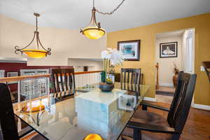 Dining room with real wood flooring, glass dining table, and small wine fridge.