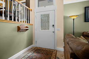 Foyer entrance with slate flooring, solid wood front door, and open entry to family room.