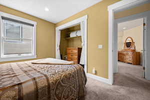 Additional guest bedroom with queen bed, storm window, and open closet with dresser.