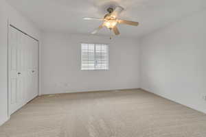 Unfurnished bedroom with light colored carpet, a closet, and ceiling fan