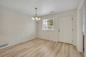 Foyer entrance with light wood-style flooring and a chandelier