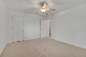 Unfurnished bedroom with light carpet and a ceiling fan