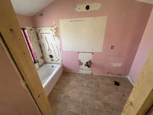 Bathroom featuring washtub / shower combination and lofted ceiling