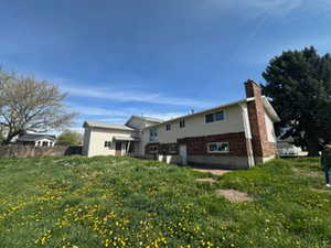 Back of house with a chimney and a yard
