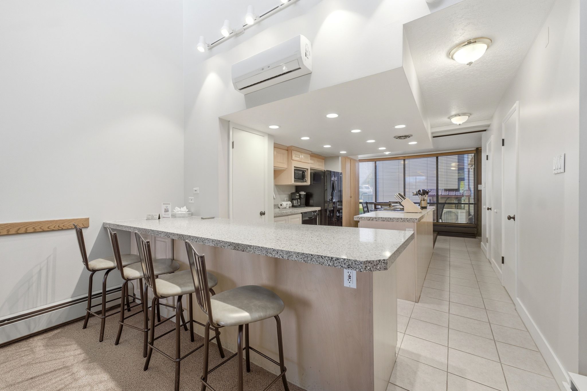 Kitchen featuring a stone-look breakfast bar with seating, recessed lighting, wood cabinetry, and a full suite of appliances