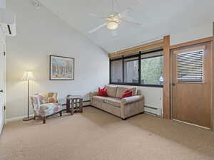 Living area featuring vaulted ceiling, light colored carpet, a ceiling fan, and a baseboard radiator