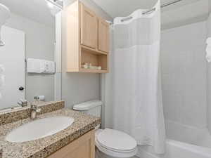 Bathroom with vanity, shower / tub combo, and a textured ceiling