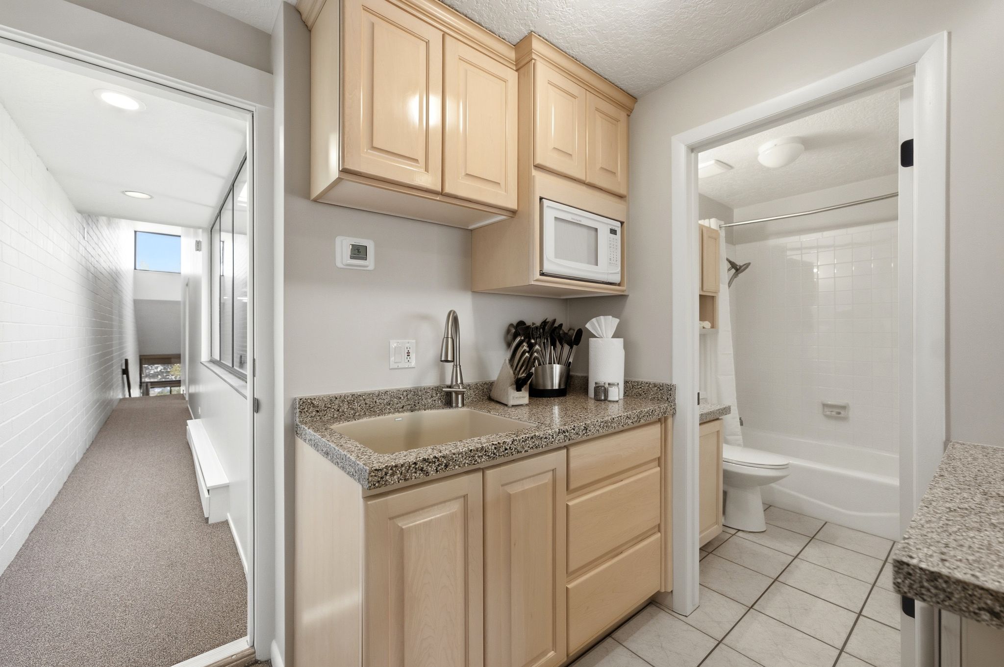 Compact kitchen area featuring wood-finish cabinetry, speckled countertop, and a built-in microwave