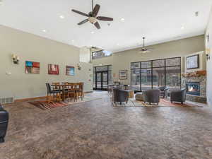 Living room with a high ceiling, recessed lighting, ceiling fan, and a fireplace