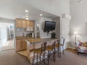 Kitchen featuring light carpet, a breakfast bar area, light wood finish cabinets, a peninsula, and white microwave