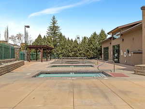 View of swimming pool featuring a jacuzzi, a pergola, and patio surround
