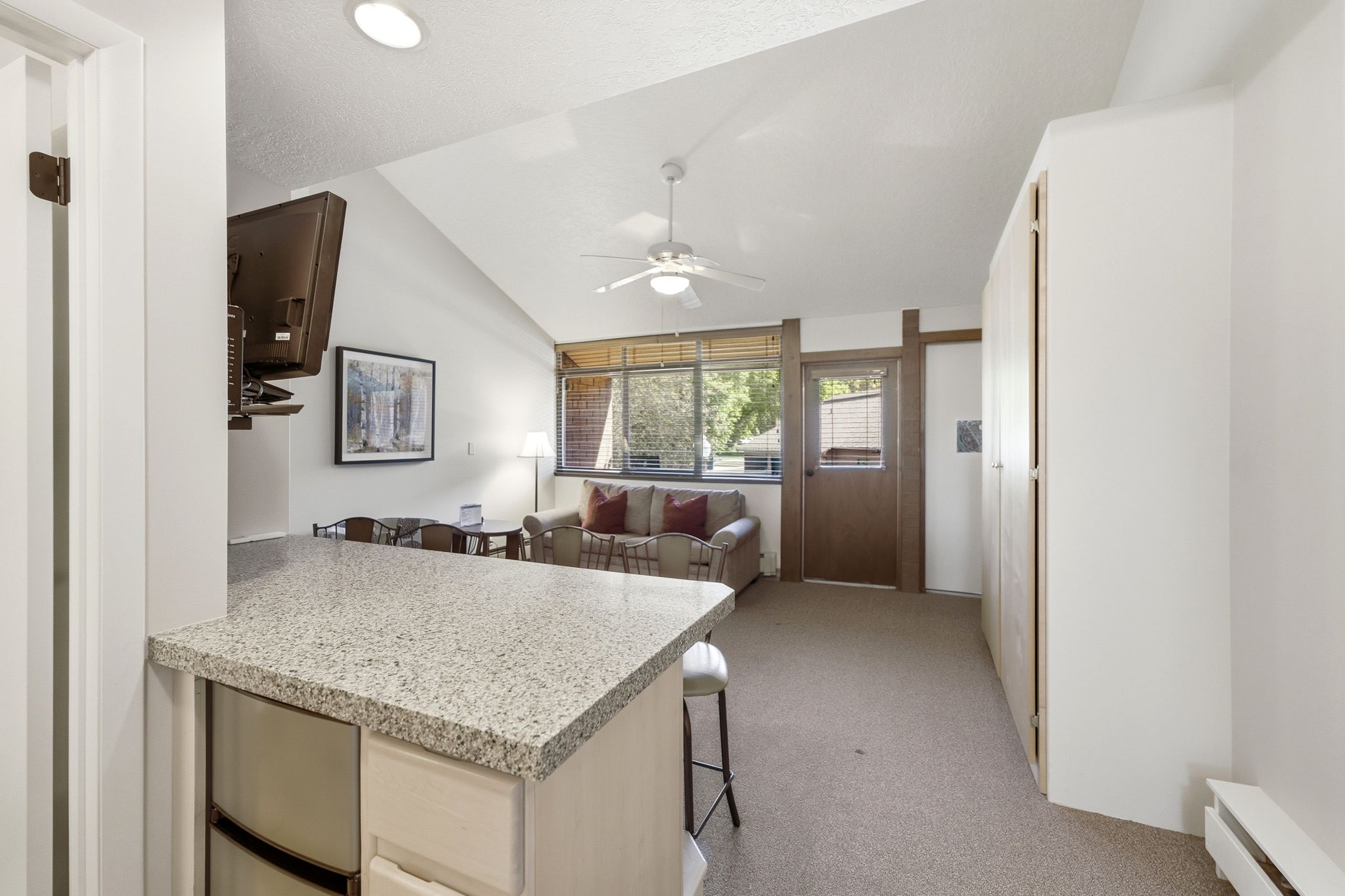 Open-concept living area with a vaulted ceiling and textured carpeting