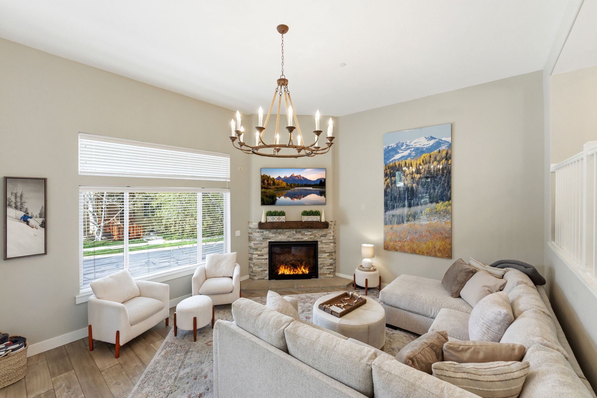 Living room with wood-type flooring, suspended lighting, and a stone fireplace