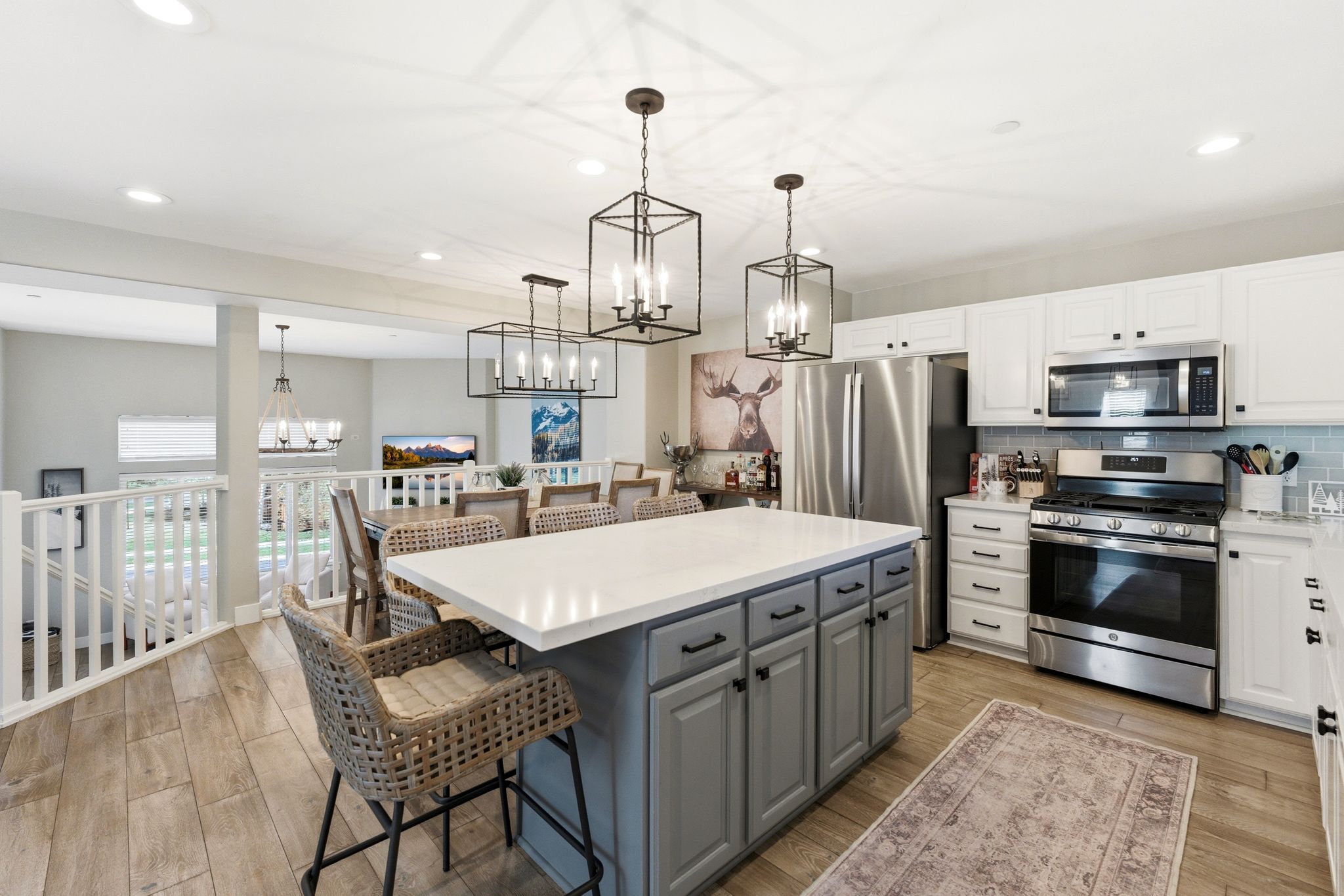 Kitchen with two tone cabinets, stainless steel appliances, a breakfast bar, light wood finished floors, and a kitchen island