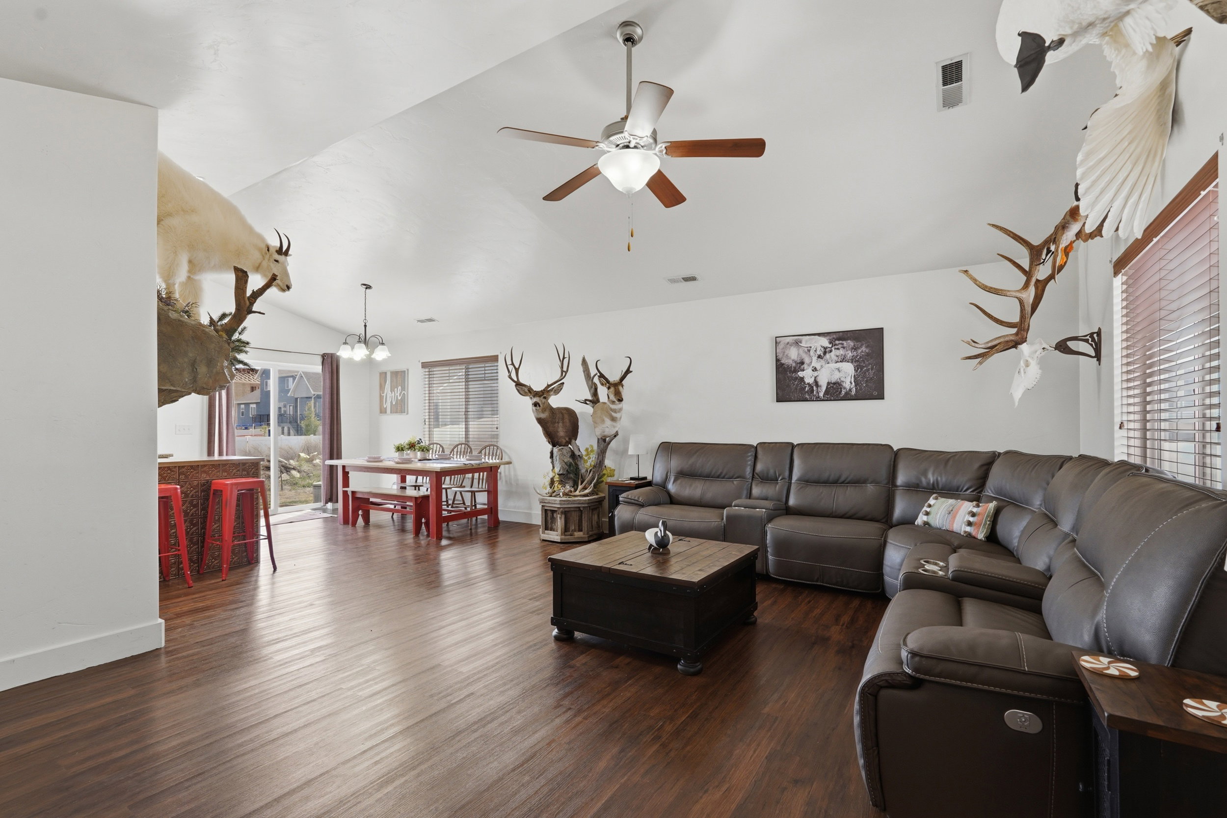 Living area featuring dark wood-style floors, lofted ceiling, ceiling fan, a chandelier, and plenty of natural light