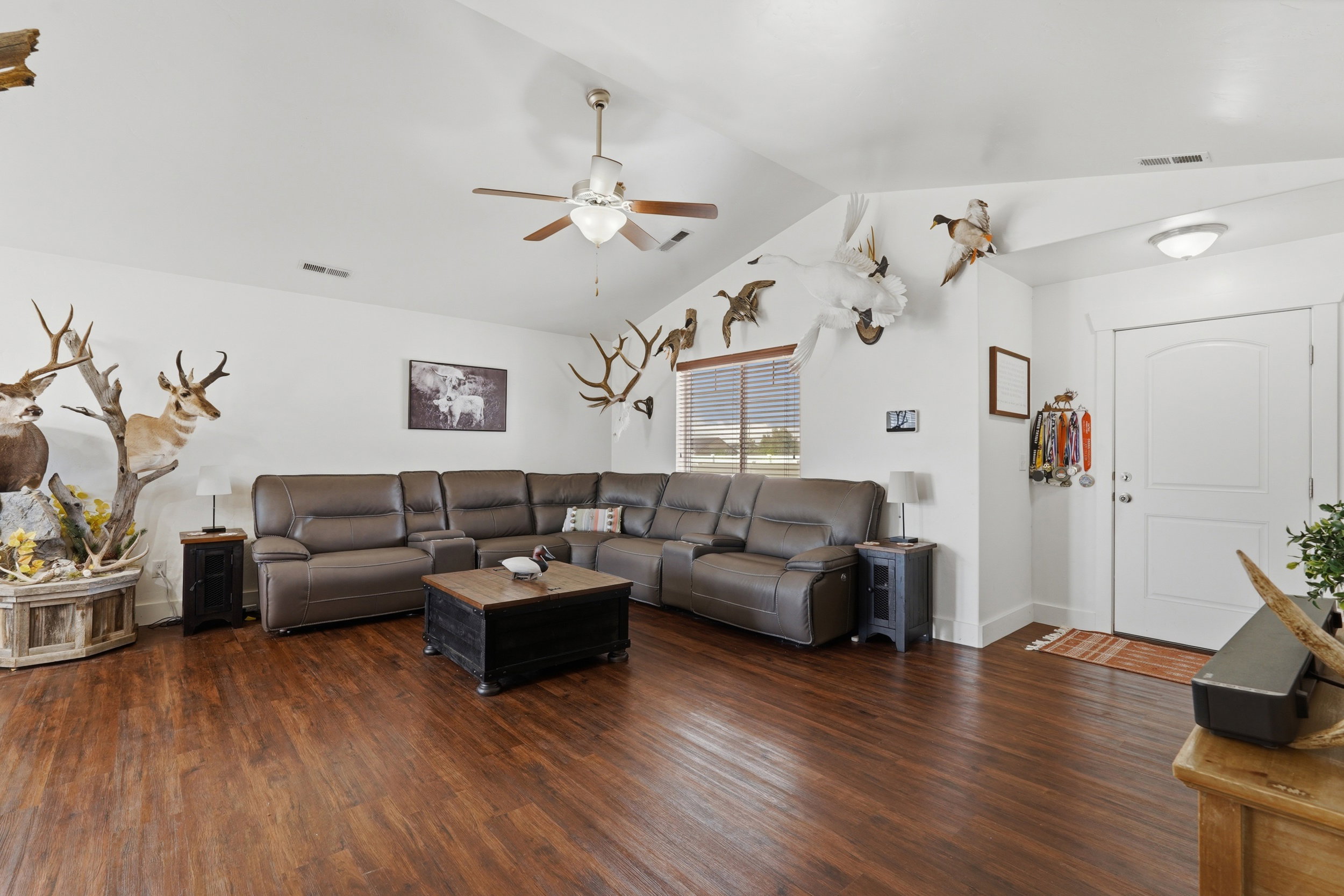Living area with dark wood-style flooring, a ceiling fan, and lofted ceiling