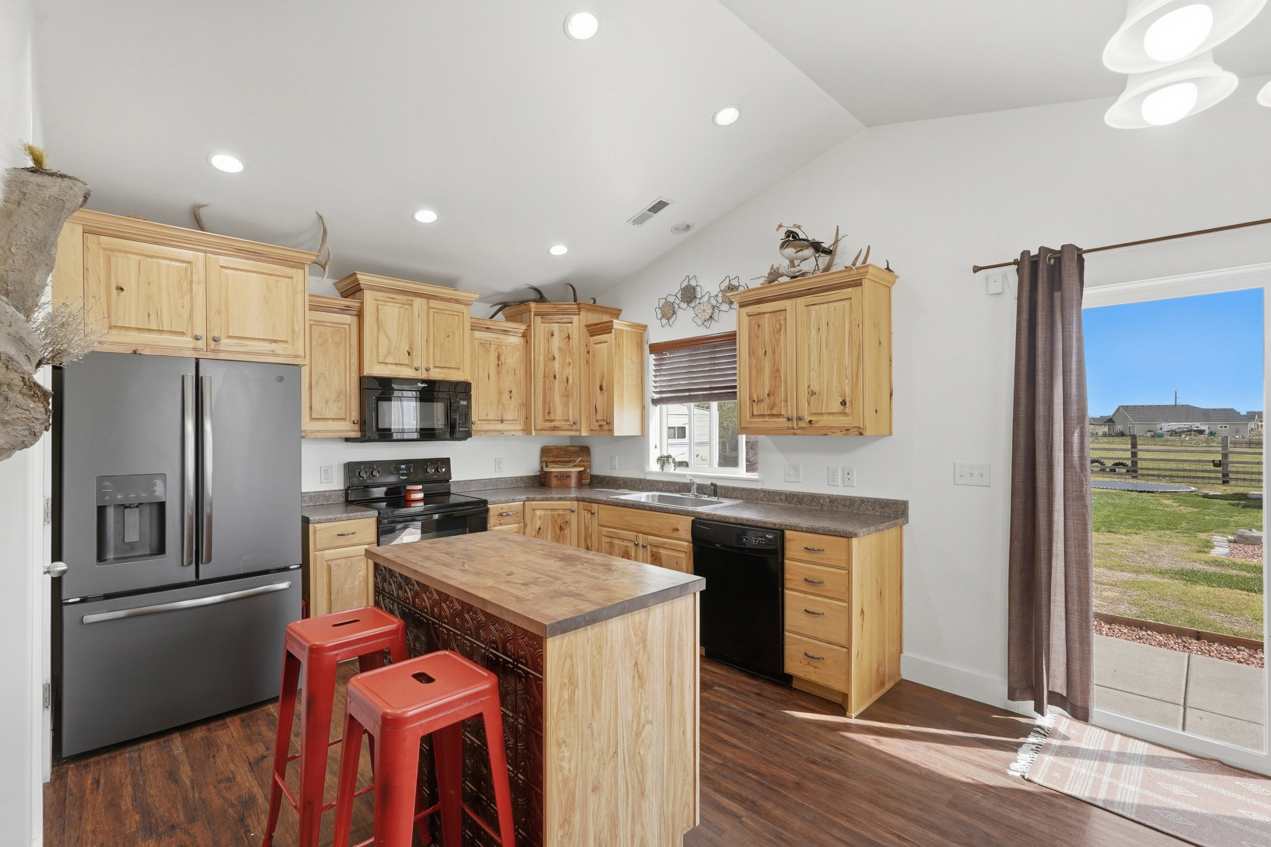 Kitchen featuring black appliances, light wood finish cabinetry, dark wood finished floors, lofted ceiling, and recessed lighting