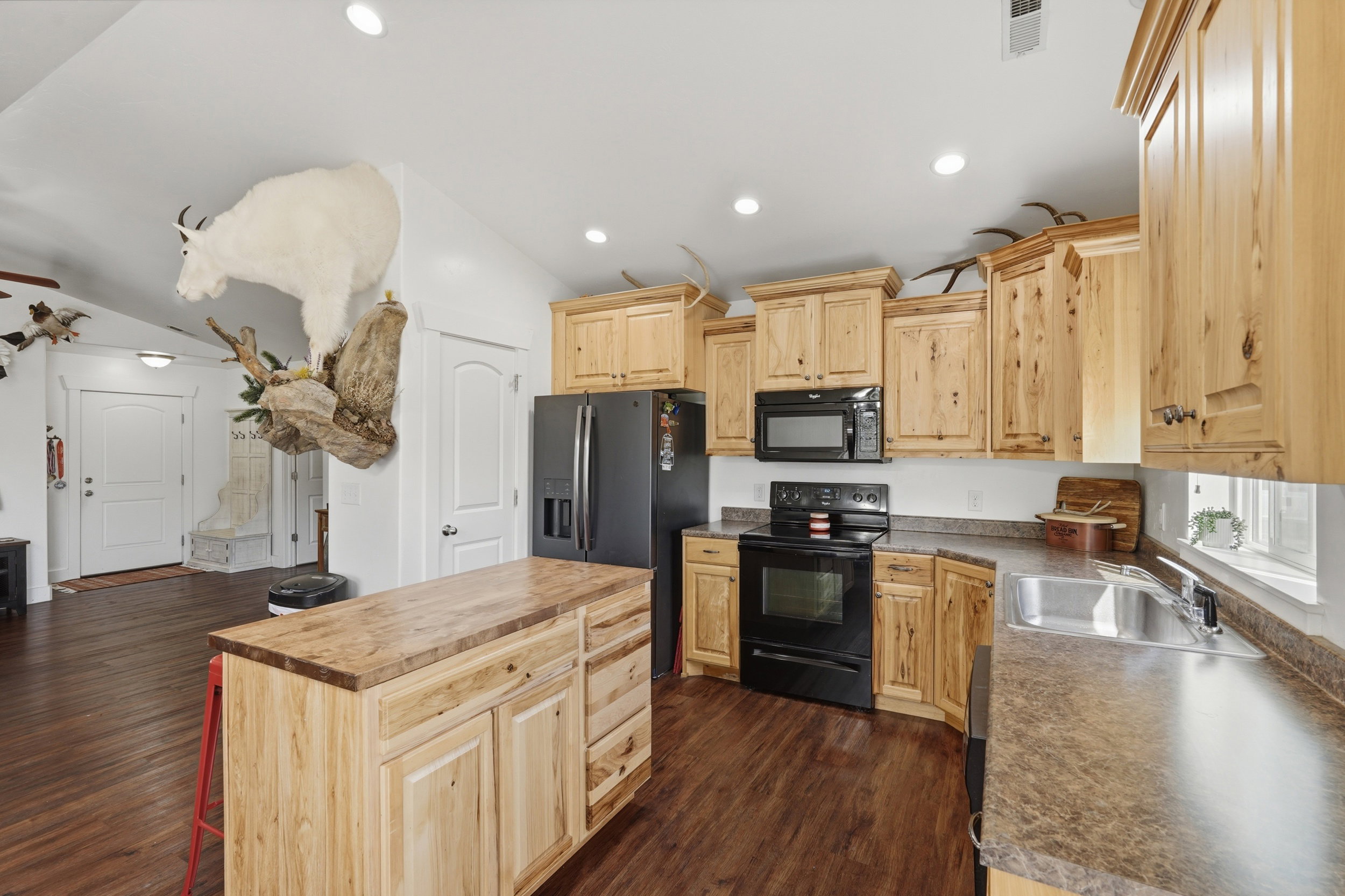 Kitchen featuring light wood finish cabinets, wooden counters, black appliances, dark wood-style flooring, and recessed lighting