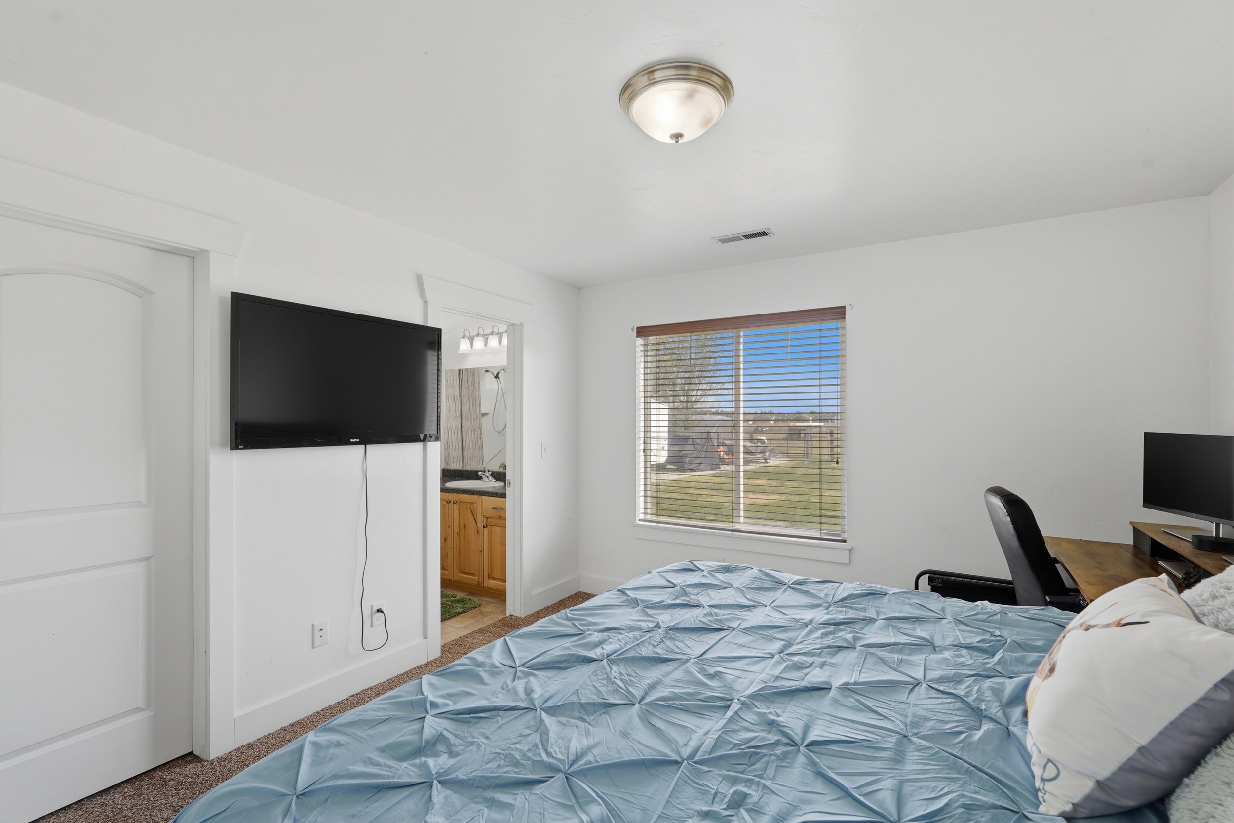 Bedroom with ensuite bath, a desk, and carpet floors