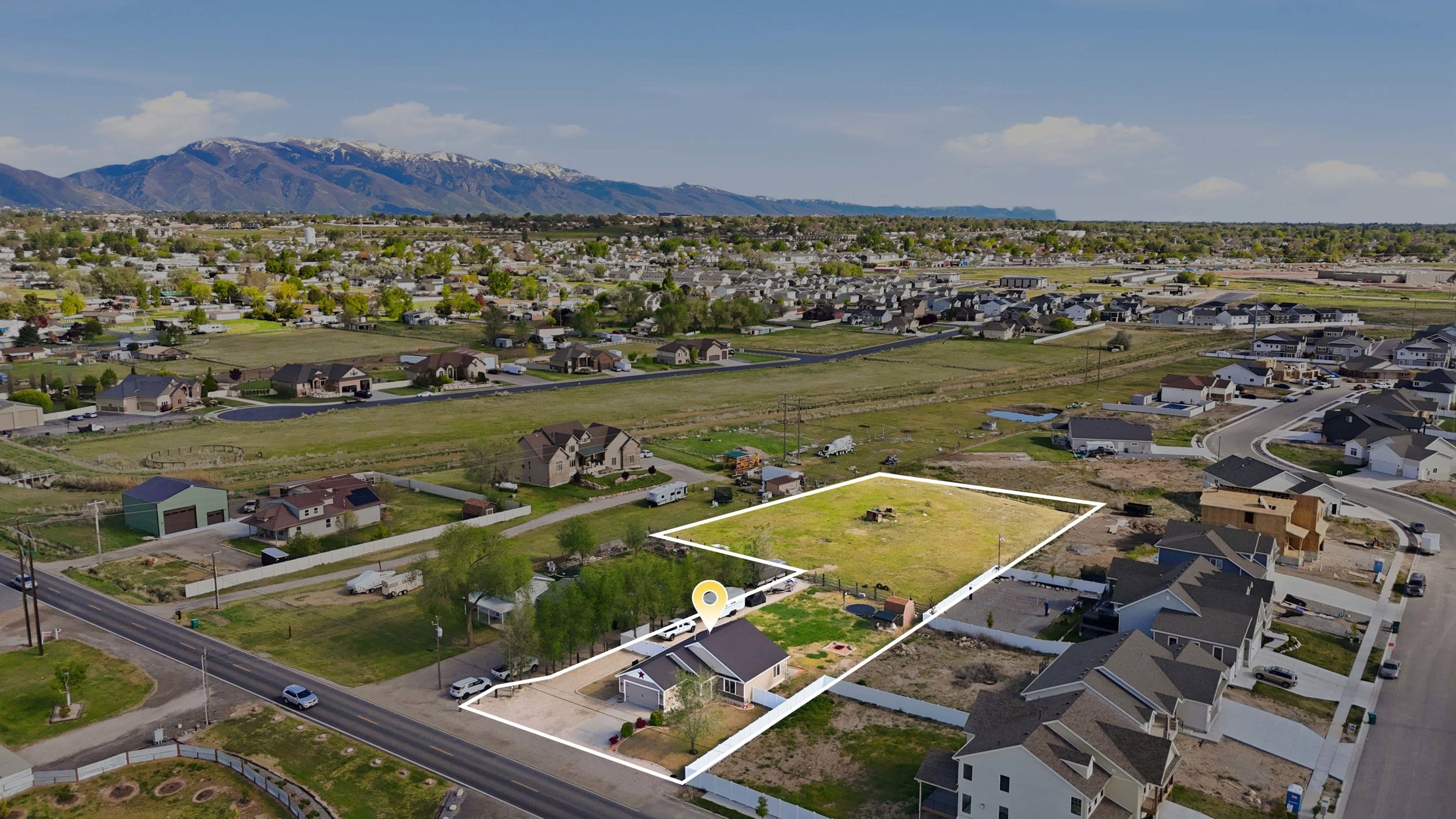Aerial view of residential area featuring property boundaries highlighted and a mountain backdrop