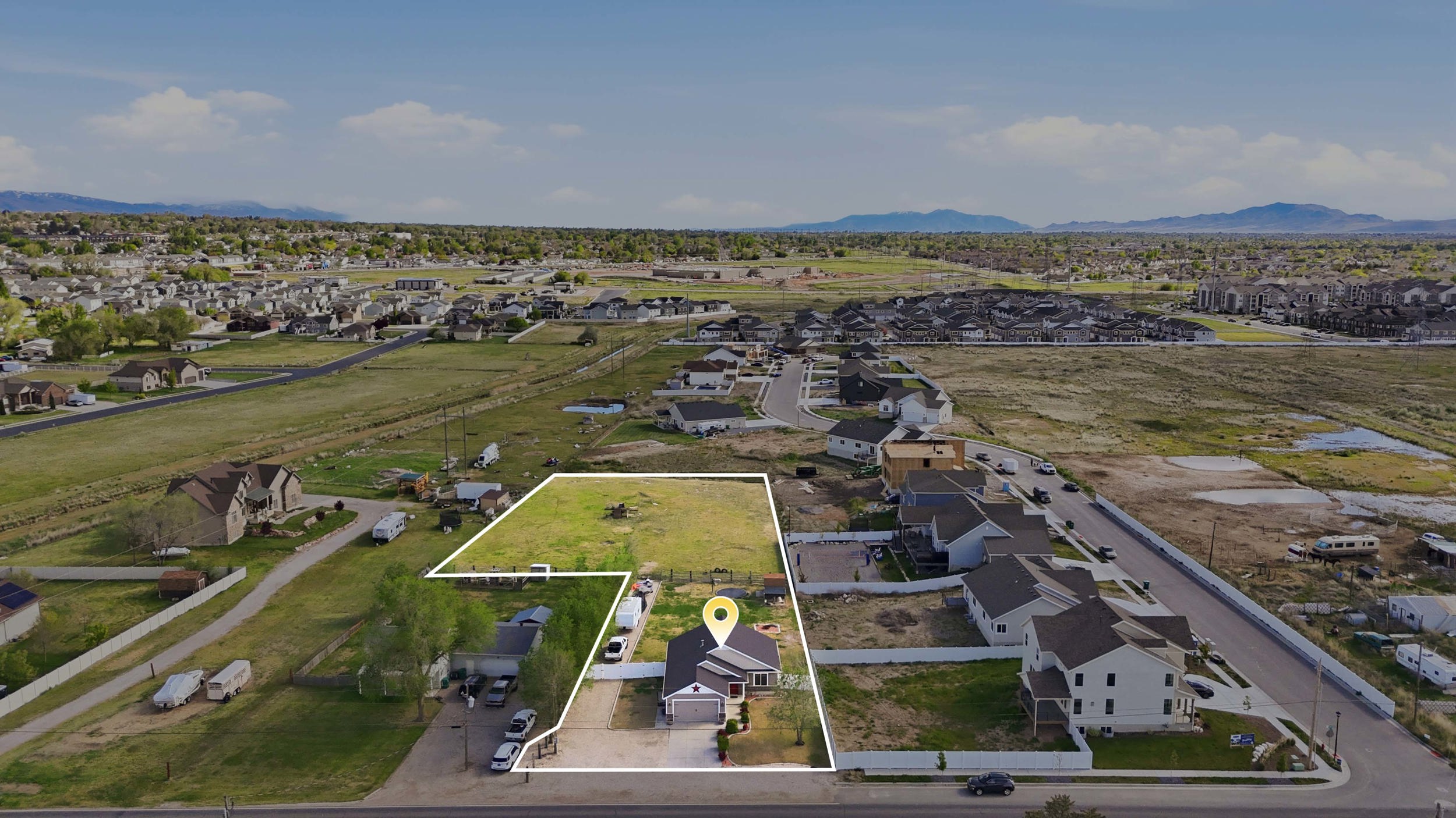 Aerial perspective of suburban area with property parcel outlined and mountains