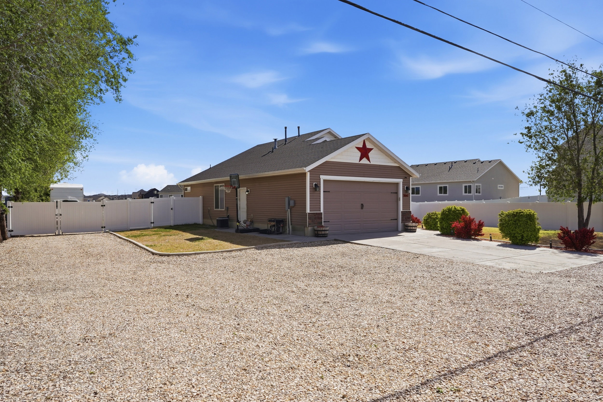 Corner view of house with a gate and driveway