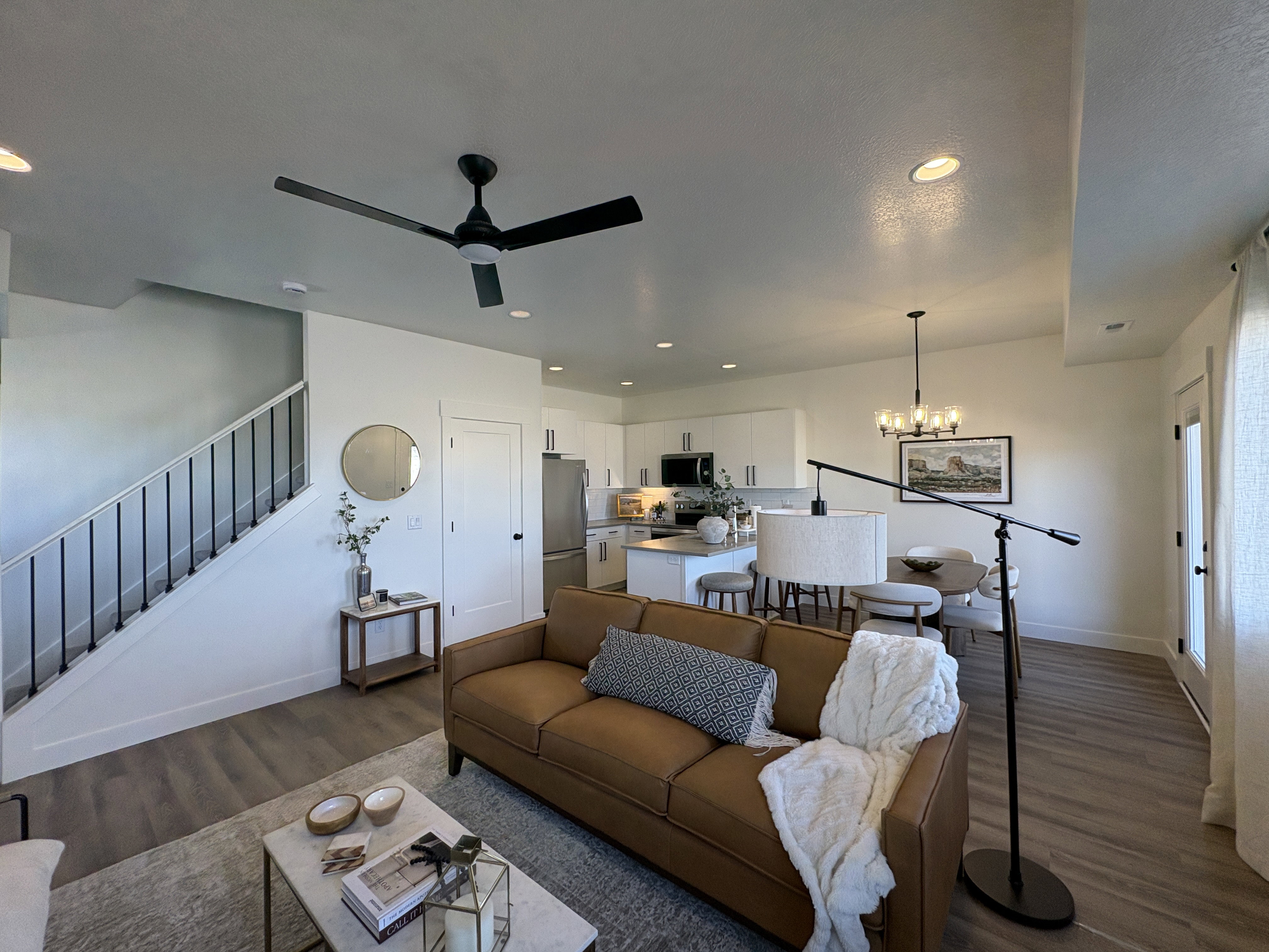 Living area featuring dark wood-style flooring, suspended lighting, and ceiling fan