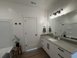 Bathroom with vanity, dark wood-style floors, and bathtub / shower combination