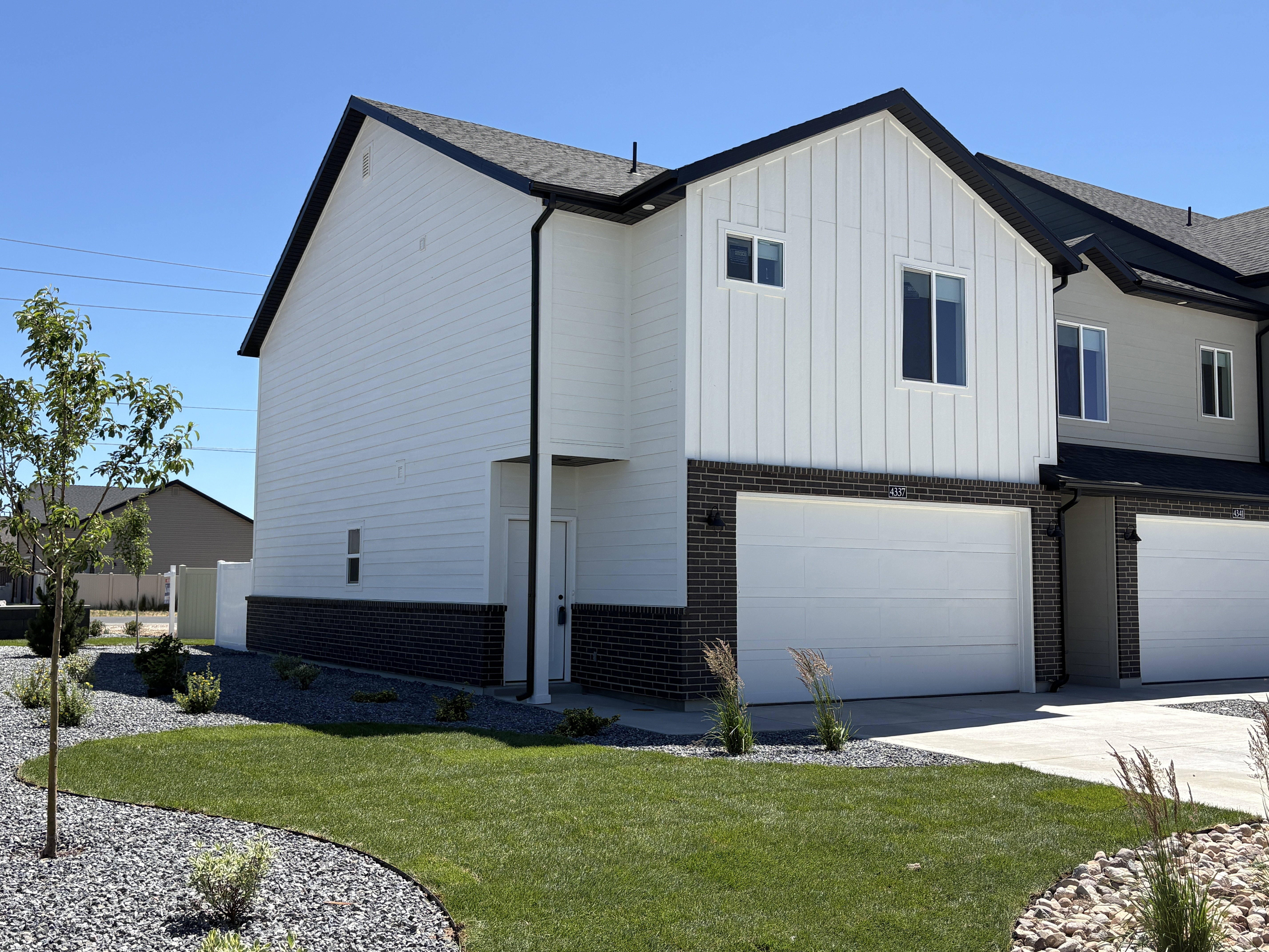 Modern townhome exterior featuring white horizontal siding and vertical paneling