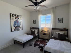 Carpeted bedroom with ceiling fan and baseboards