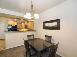 Dining area featuring a contemporary chandelier and plush carpeting
