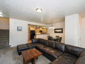 Open-concept living space featuring a carpeted floor, recessed and flush mount lighting, and a staircase with matching carpet