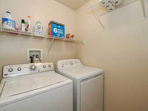 Dedicated utility space featuring two white laundry appliances and a wall-mounted wire shelving system