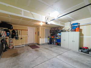 Spacious garage featuring a concrete floor, exposed ceiling joists, and multiple built-in storage solutions