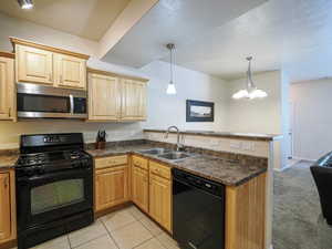 Kitchen featuring light wood cabinetry, a stainless steel over-the-range microwave, black gas range, and a dual basin sink with a chrome faucet