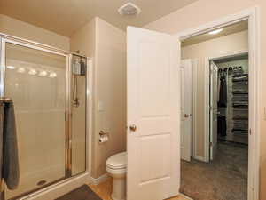 Bathroom featuring a glass-enclosed shower, toilet, and light beige wall paint