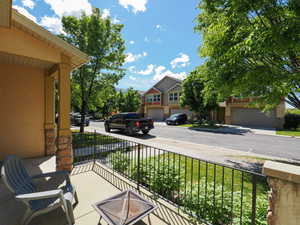 Covered front porch featuring stone-clad columns and a wrought iron railing