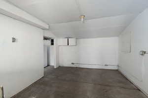 Workshop / storage area in exterior building featuring unfinished concrete floors.