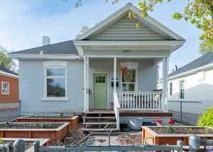 View of front of home featuring garden beds, a covered porch, and painted brick