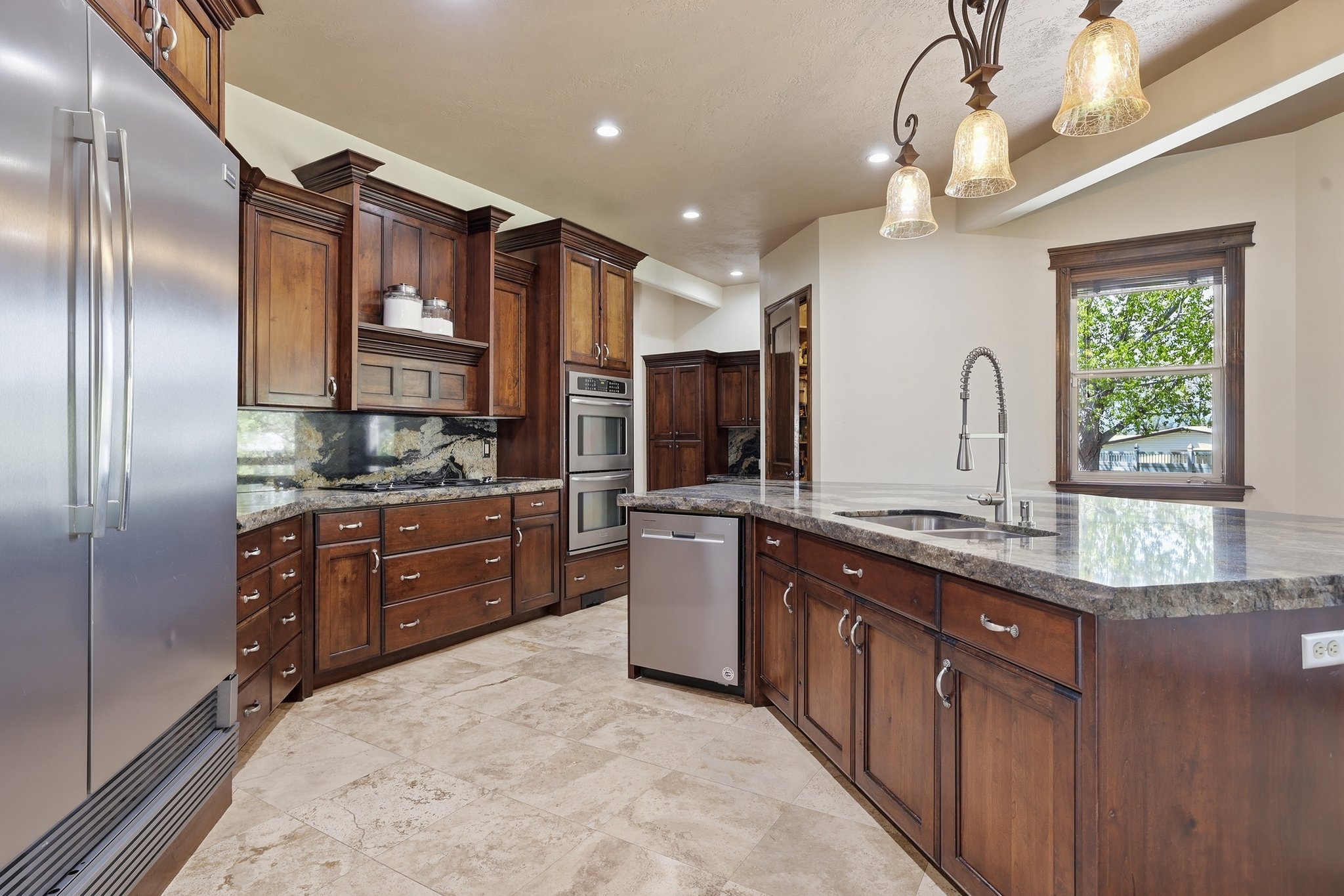 Kitchen featuring dark wood cabinetry, stainless steel appliances, stone countertops, and tile flooring