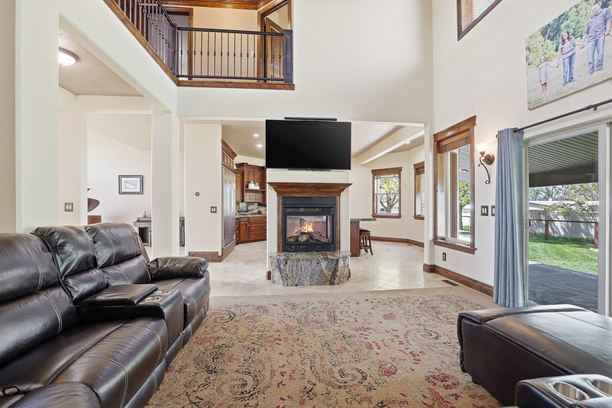 Vaulted ceilings in this living space feature a stone-clad fireplace with a wood-finished mantel