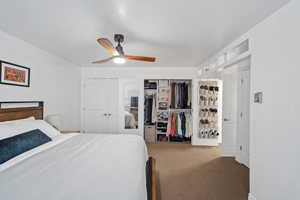 Carpeted bedroom with a ceiling fan and a closet