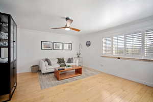 Living room featuring light wood finished floors, ornamental molding, and a ceiling fan