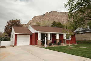 View of front facade with a shingled roof, concrete driveway, a mountain view, and a garage
