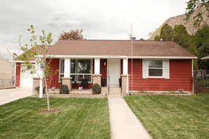 View of front of house with a porch, a shingled roof, and a front yard