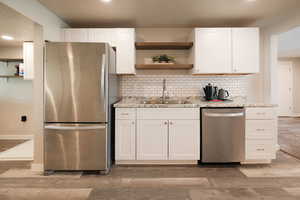 Kitchen featuring open shelves, stainless steel appliances, light wood-style floors, and recessed lighting